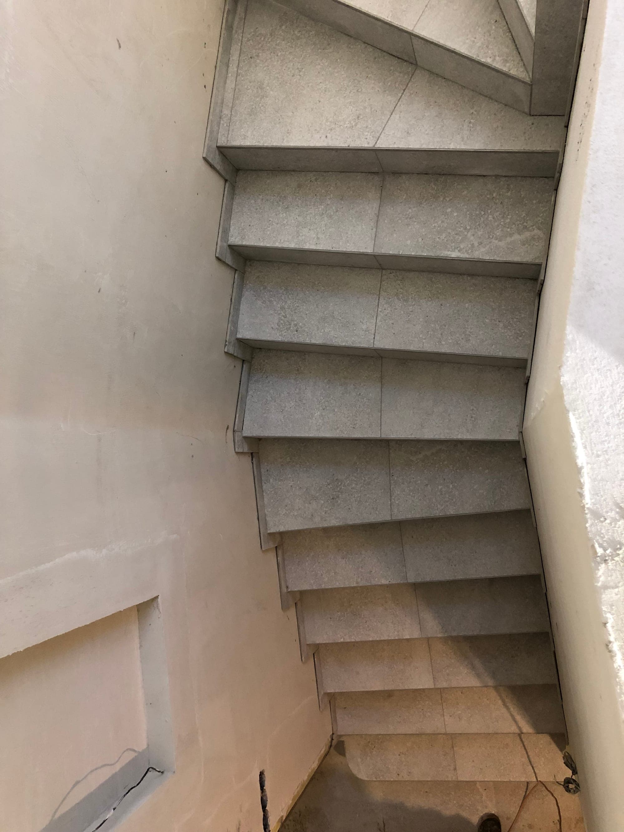 Točité schodisko s obloženými klinovými stupňami v svetlom kamennom dekore