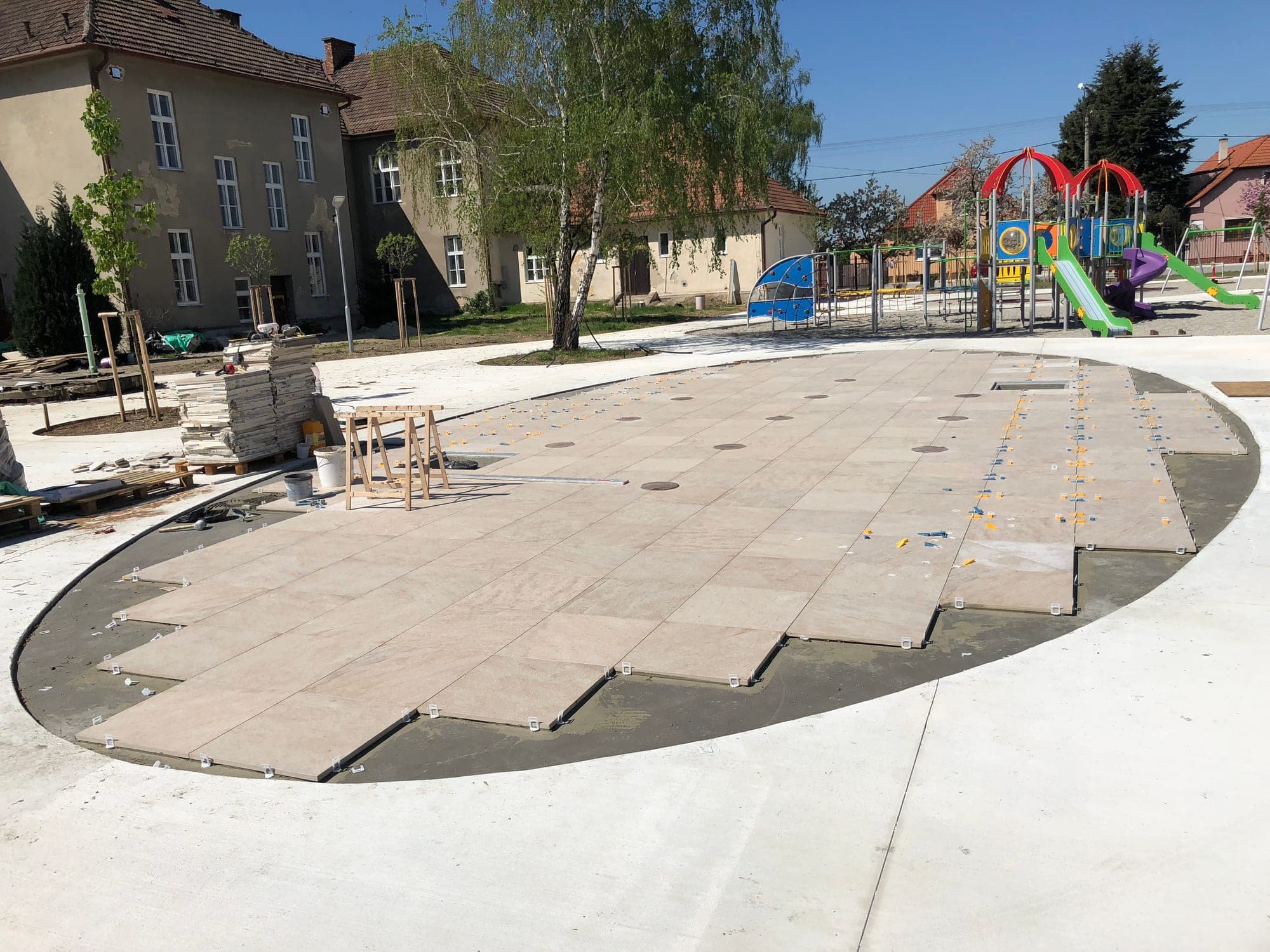 Kladenie veľkoformátovej dlažby na kruhovej ploche počas realizácie