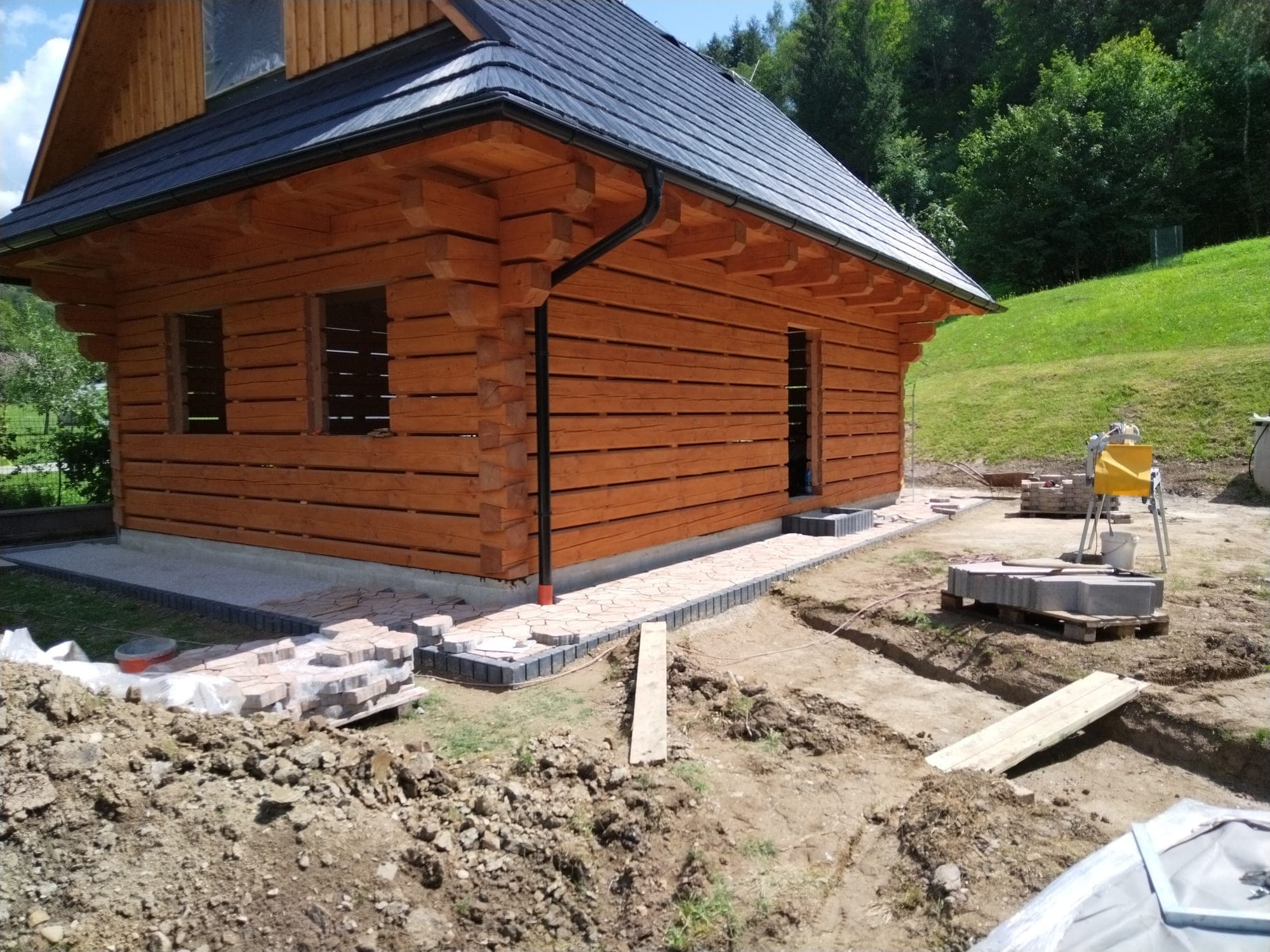 Spevnená plocha pred vstupom do zrubovej chaty s výhľadom do horského terénu