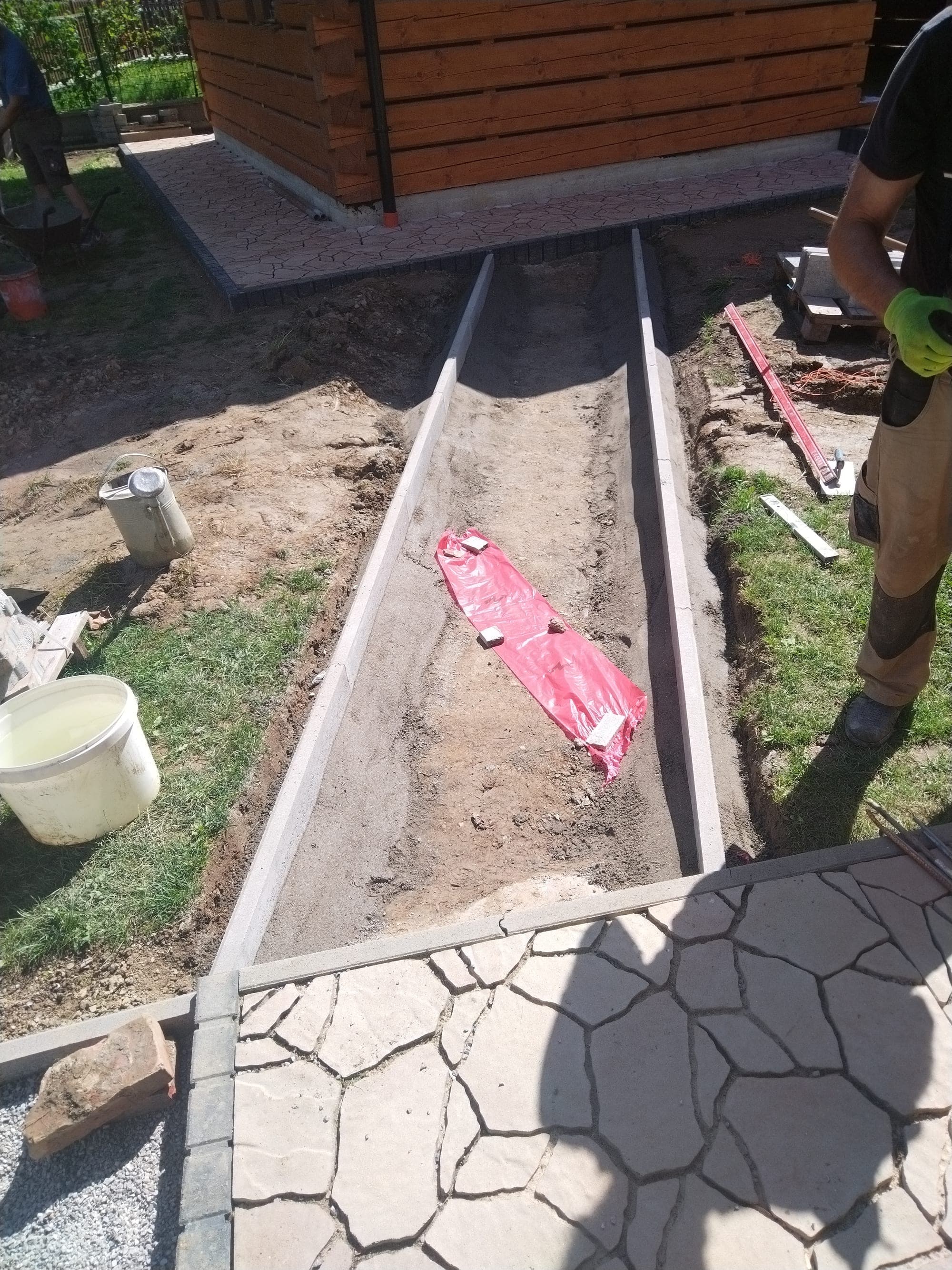 Osadzovanie obrubníka do betónového lôžka pozdĺž budúceho chodníka